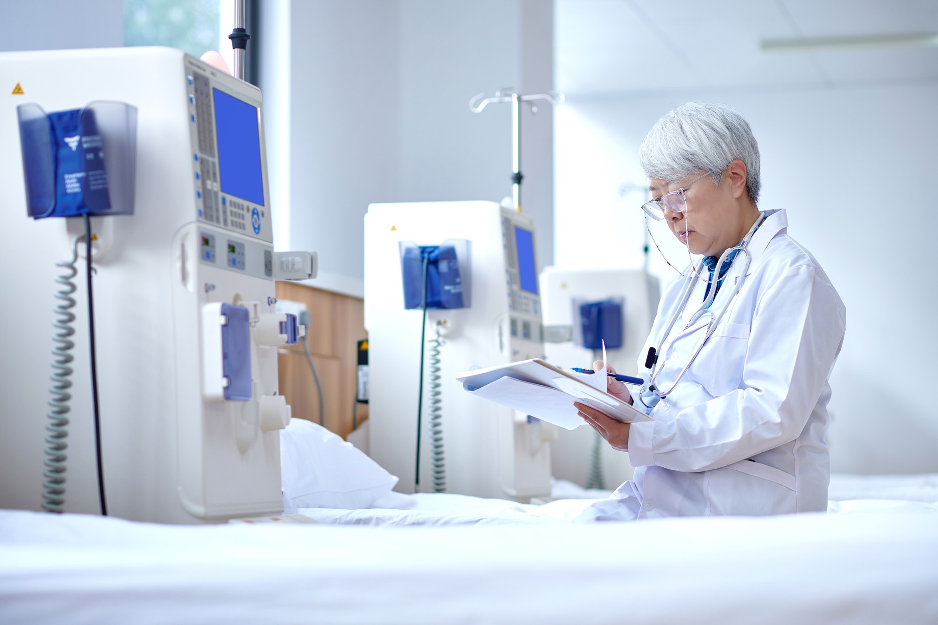 Asian Senior Doctor Checking Data at Hemodialysis Room